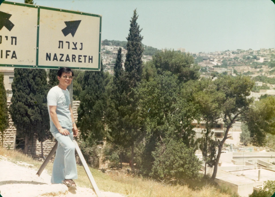 David below a road sign for Nazareth, 1977.