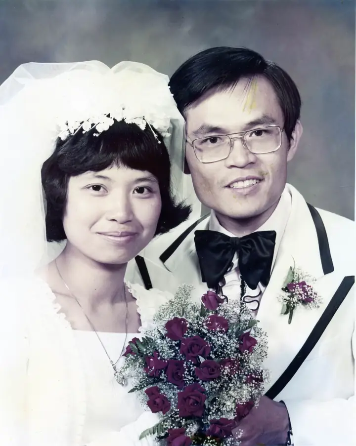 A bride and groom posing with a bouquet