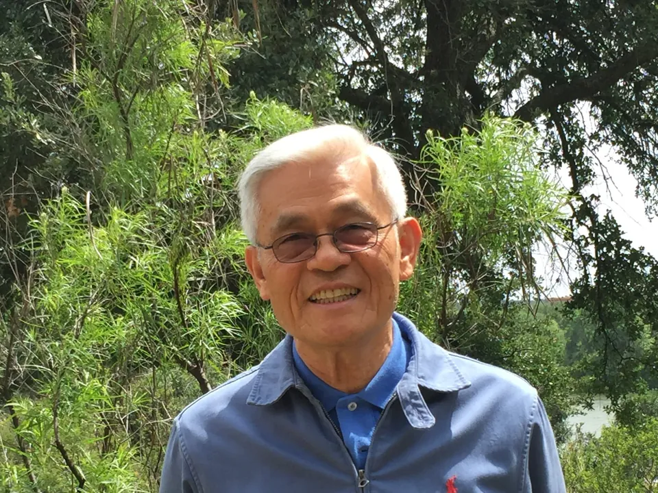 David Tsang smiling outdoors, wearing glasses and a blue jacket